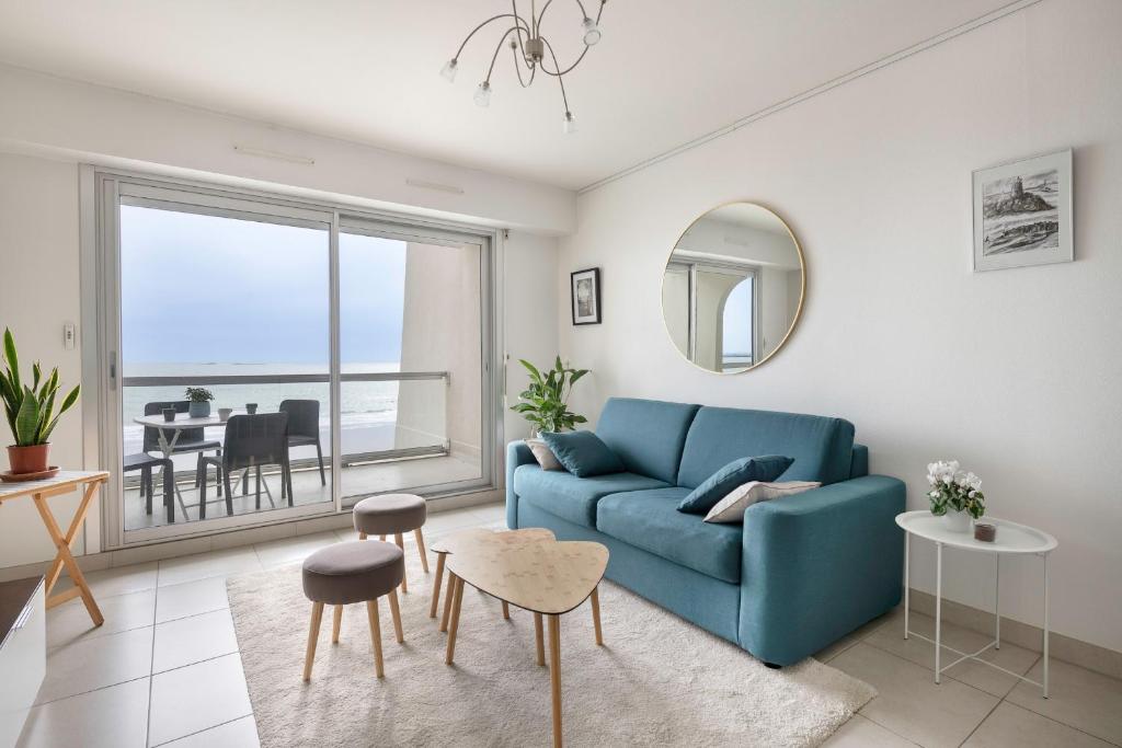 a living room with a blue couch and a table at Magnifique vue mer pour un sejour Baulois in La Baule