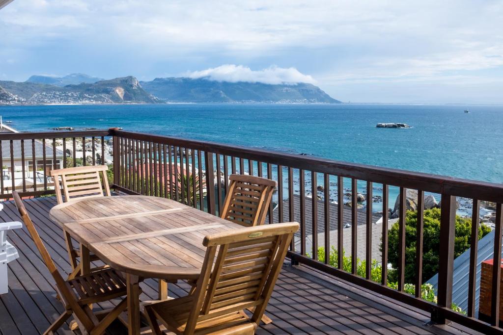 a wooden table and chairs on a balcony overlooking the ocean at Boulders Beach House in Simonʼs Town