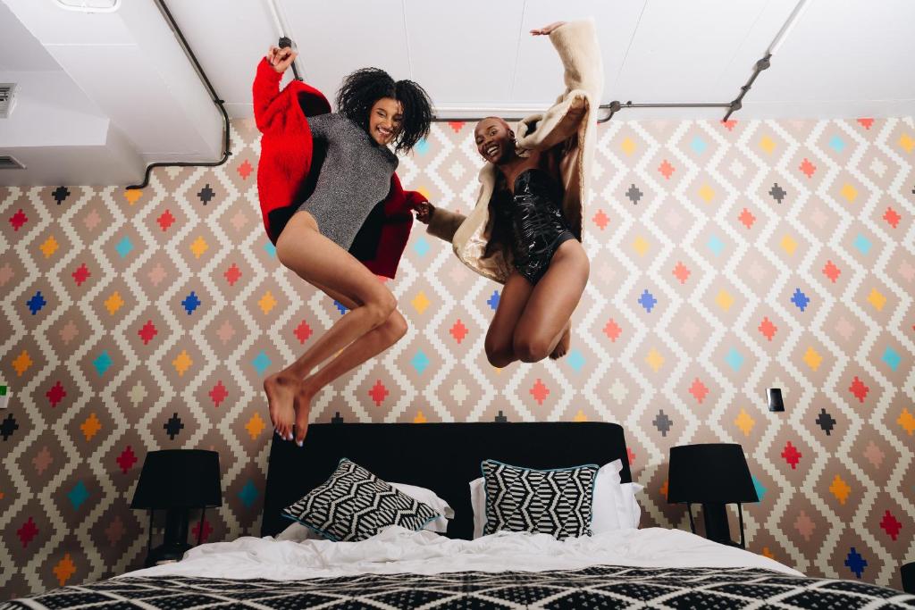 two people jumping in the air over a bed at Hallmark House Hotel in Johannesburg