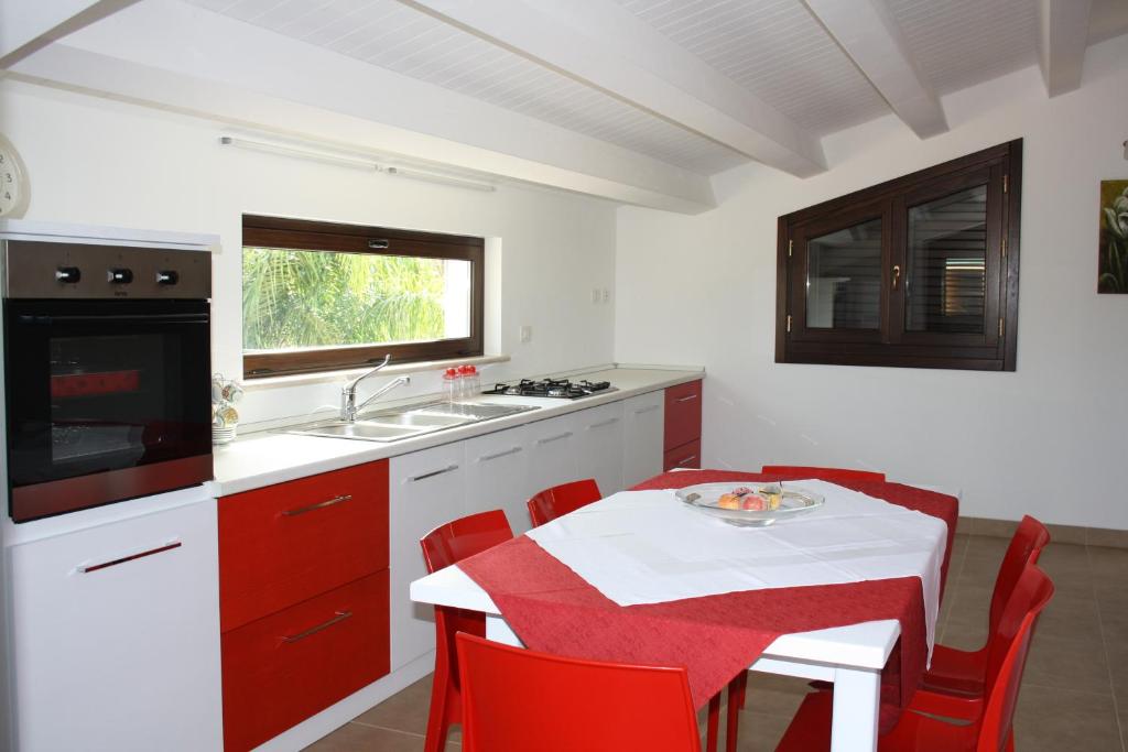 マリーナ・ディ・モーディカにあるLa Villa di Uccioのキッチン(テーブル、赤い椅子、シンク付)