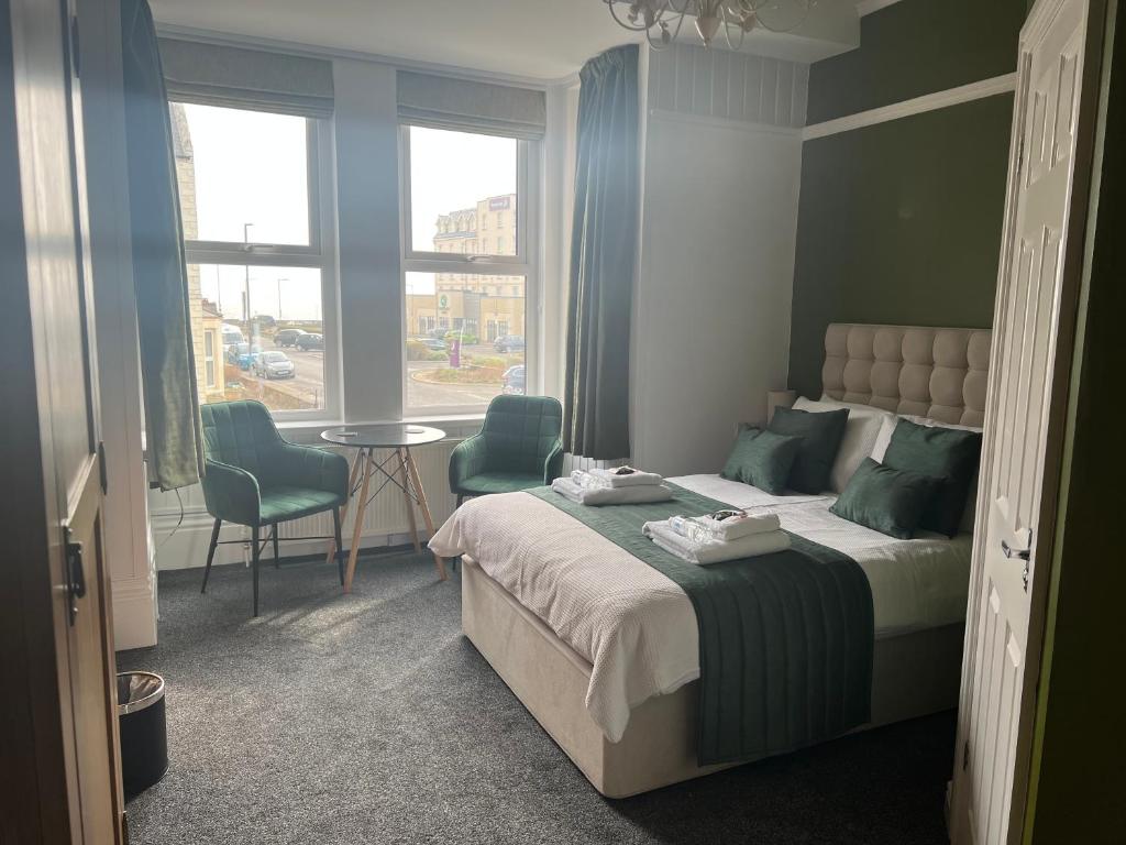 1 dormitorio con 1 cama, 2 sillas y ventana en The Promenade Guest House, en Bridlington