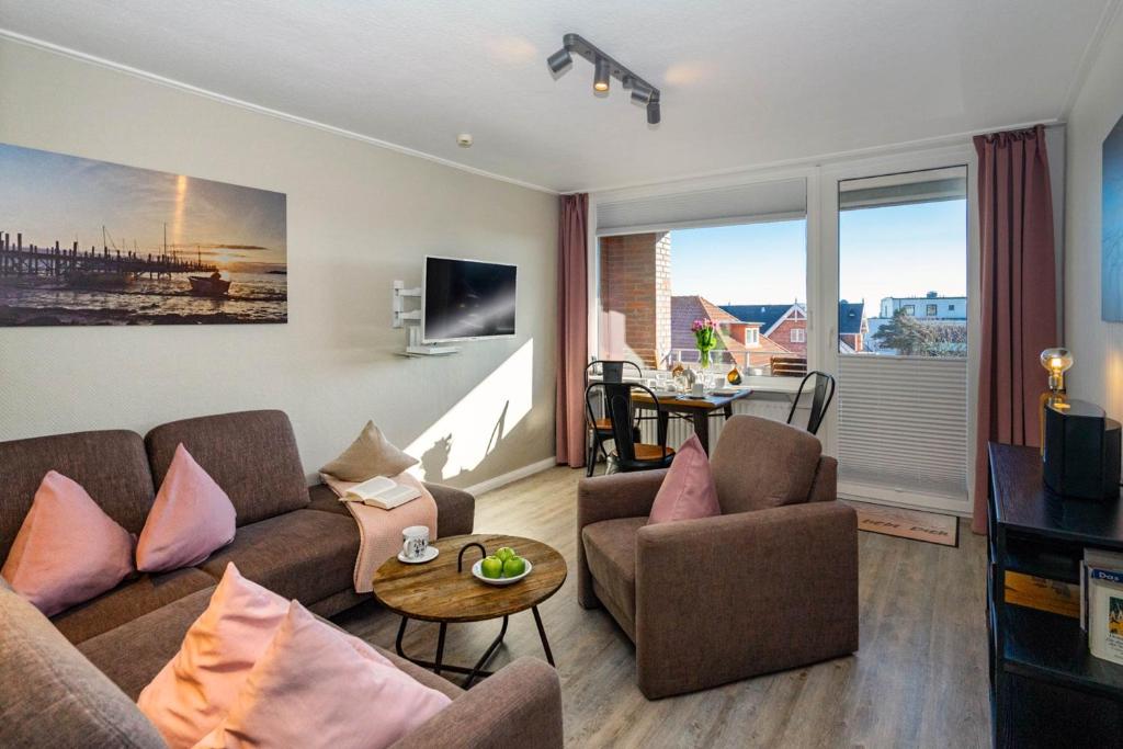 ein Wohnzimmer mit einem Sofa, Stühlen und einem Tisch in der Unterkunft Ferienwohnung Eidum Strand in Westerland