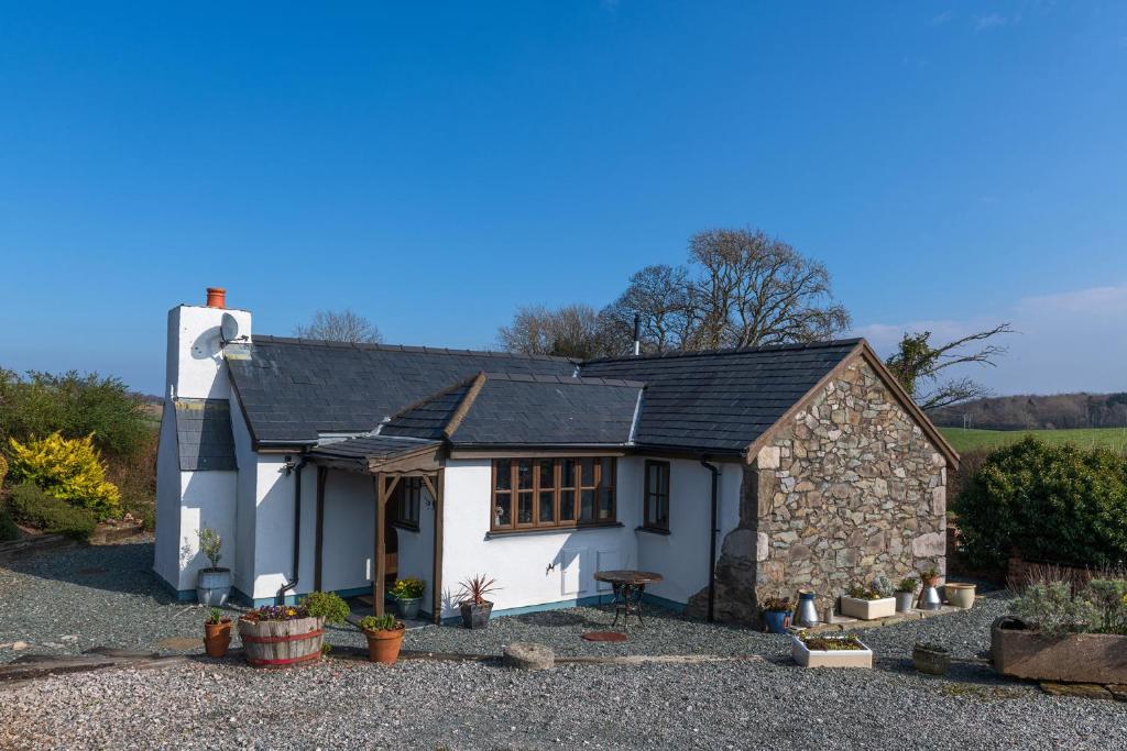 een wit huisje met een zwart dak bij Beautiful Countryside cottage on the North Wales Coast in Abergele