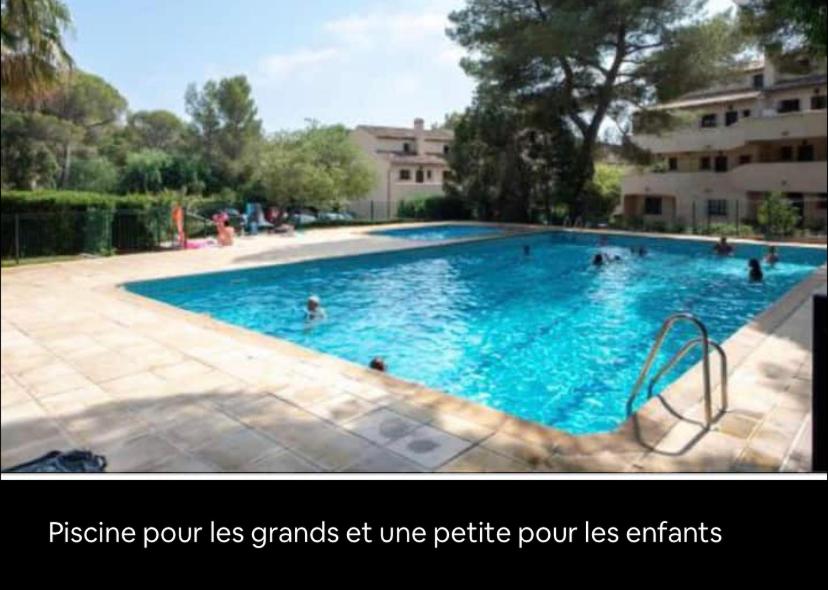 Una gran piscina con gente en el agua. en Le hameau des pins, en Boulouris-sur-Mer