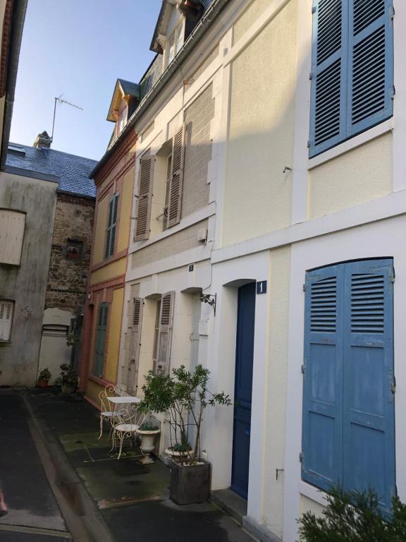 un callejón con un edificio con puertas azules y una mesa en Maison de pêcheur Trouville - Le Colibri, en Trouville-sur-Mer