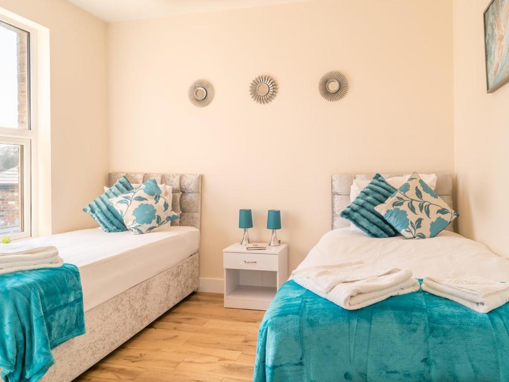 Duas camas num quarto com azul e branco em Pass the Keys Renovated Victorian Apartment In Ealing em Londres