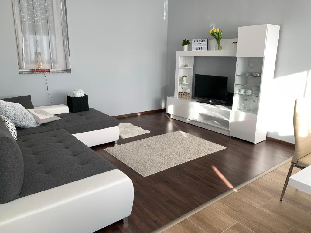 uma sala de estar com um sofá e uma televisão em Modern two bedroom flat with balcony em Lenti