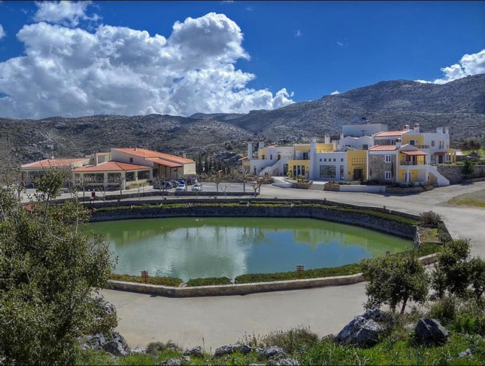 una gran piscina de agua frente a algunos edificios en Delina Mountain Resort, en Anógeia