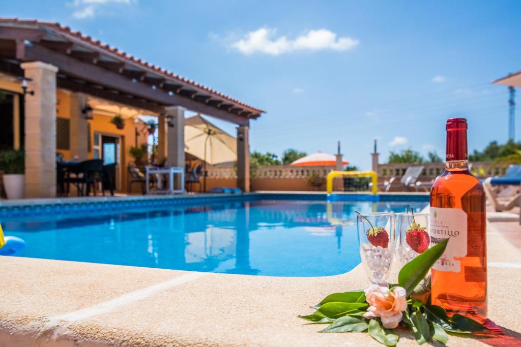 卡普德佩拉的住宿－Ideal Property Mallorca - Villa Bona Vista，一瓶葡萄酒和一杯游泳池旁的玻璃