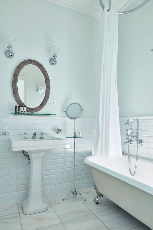 a bathroom with a sink and a tub and a mirror at Poseidonion Grand Hotel in Spetses