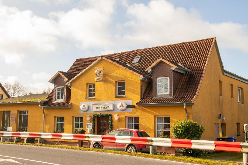 een geel gebouw met een auto ervoor geparkeerd bij Pension bei Stralsund in Prohn