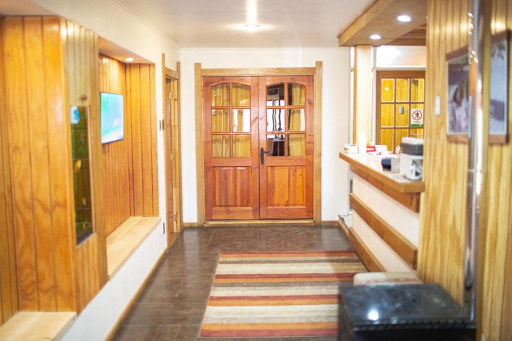 een hal met houten deuren en een gestreept tapijt bij Roble Austral Hostal in Coihaique