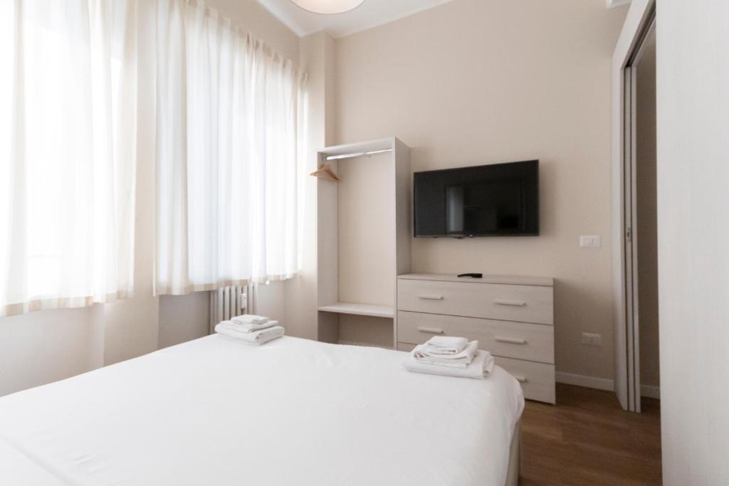 biała sypialnia z łóżkiem i telewizorem w obiekcie Via Torino Apartment 3 w Mediolanie