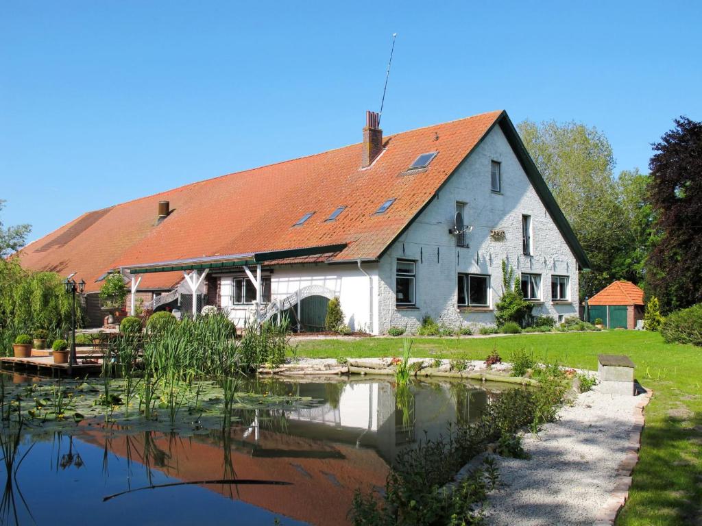 a house with a pond in front of it at Apartment Peters by Interhome in Berdumer Neue Mitteldeich