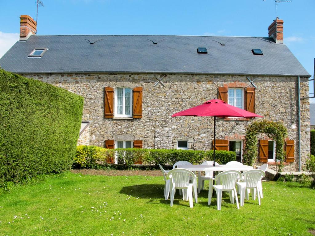 Saint-Maurice-en-CotentinにあるHoliday Home La Bonneraie - MCE401 by Interhomeの家の前の赤い傘付きテーブルと椅子