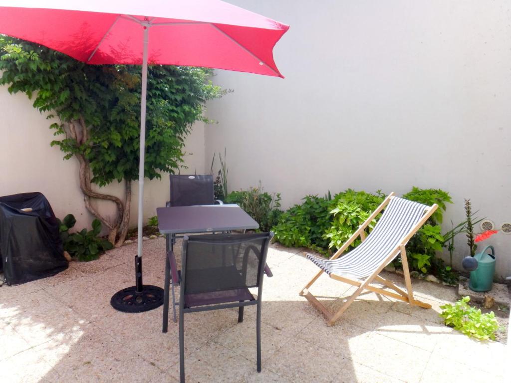 un parapluie rouge assis à côté d'une table et de chaises dans l'établissement Holiday Home La Touche - IDR120 by Interhome, à La Flotte