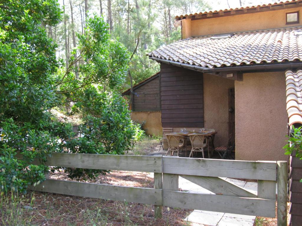 a house with a table and a fence in front of it at Holiday Home Les maisons de la forêt by Interhome in Lacanau-Océan