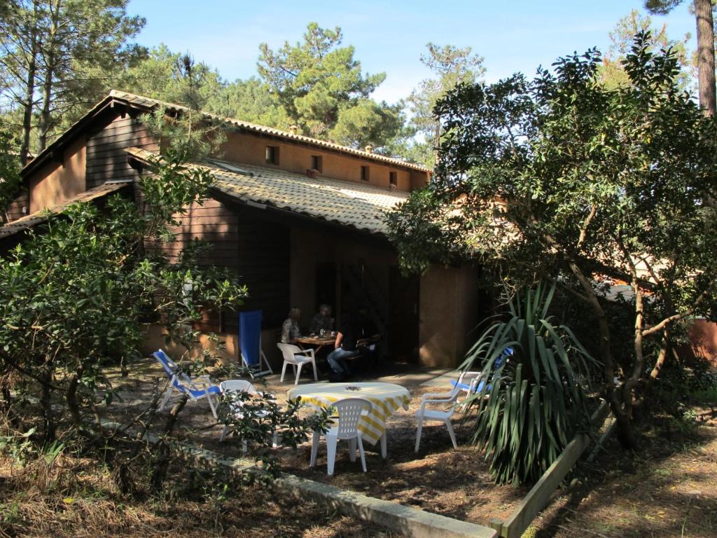 a group of people sitting at a table outside of a house at Holiday Home Les maisons de la forêt by Interhome in Lacanau-Océan