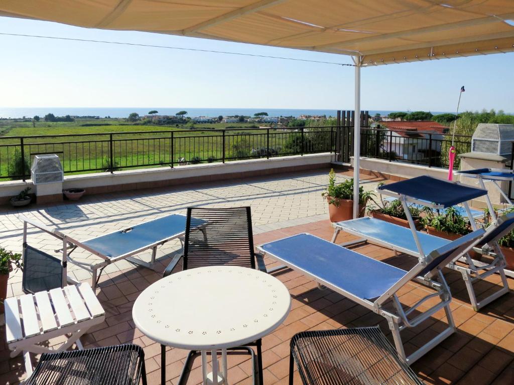 a patio with chairs and tables and an umbrella at Apartment Algamarina by Interhome in Cerveteri