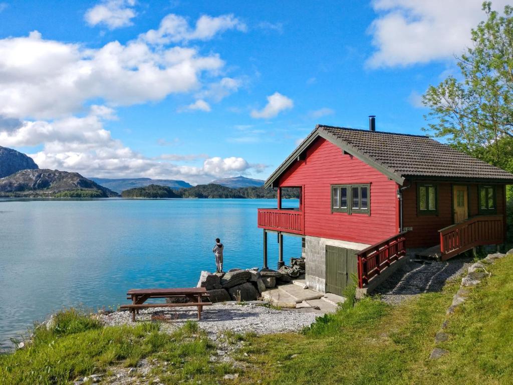 une maison rouge sur la rive d'une masse d'eau dans l'établissement Holiday Home Idun - FJS131 by Interhome, à Hyllestad