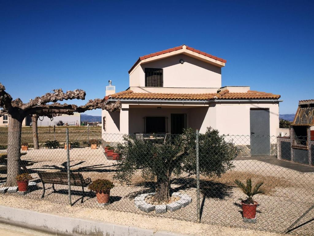 a small white house with trees and a fence at Casa Laura in Deltebre
