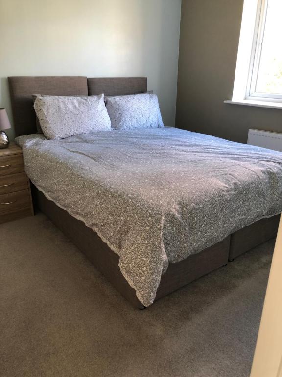 uma cama grande num quarto com uma colcha em Hill House - 5 Mins Merry Hill - Perfect for Contractors & Families em Brettell Lane