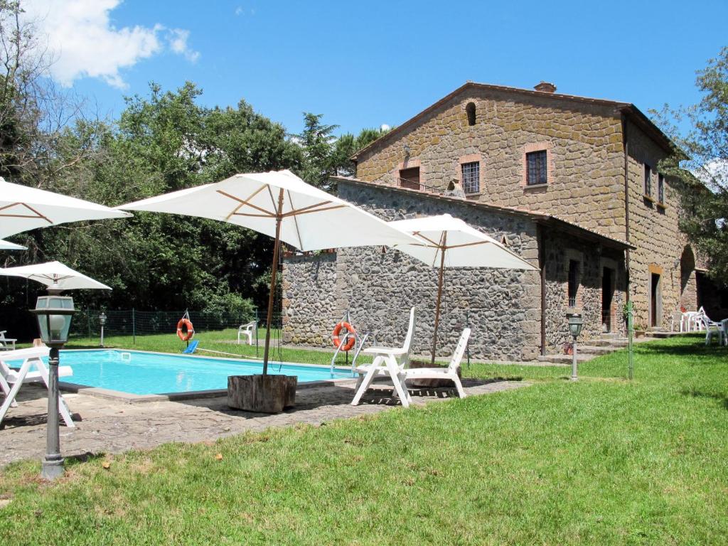 a pool with umbrellas next to a building at Apartment La Capraccia-5 by Interhome in Bagnoregio