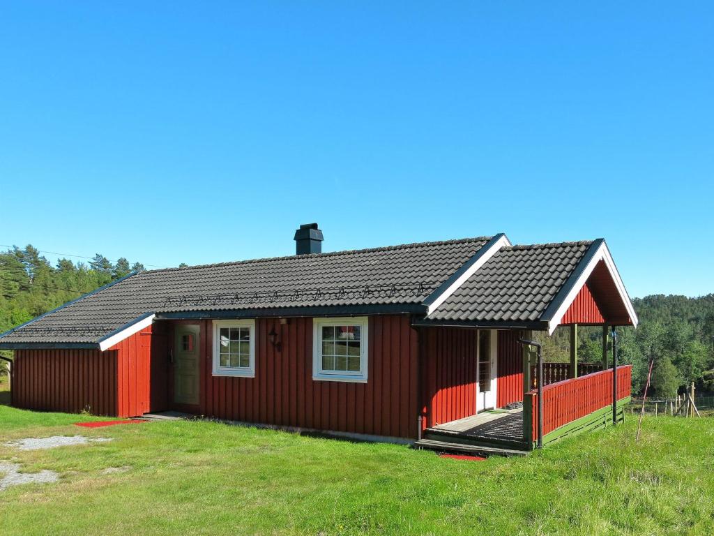 une maison rouge avec un toit noir dans un champ dans l'établissement Chalet Espetveit - SOO351 by Interhome, à Hornnes