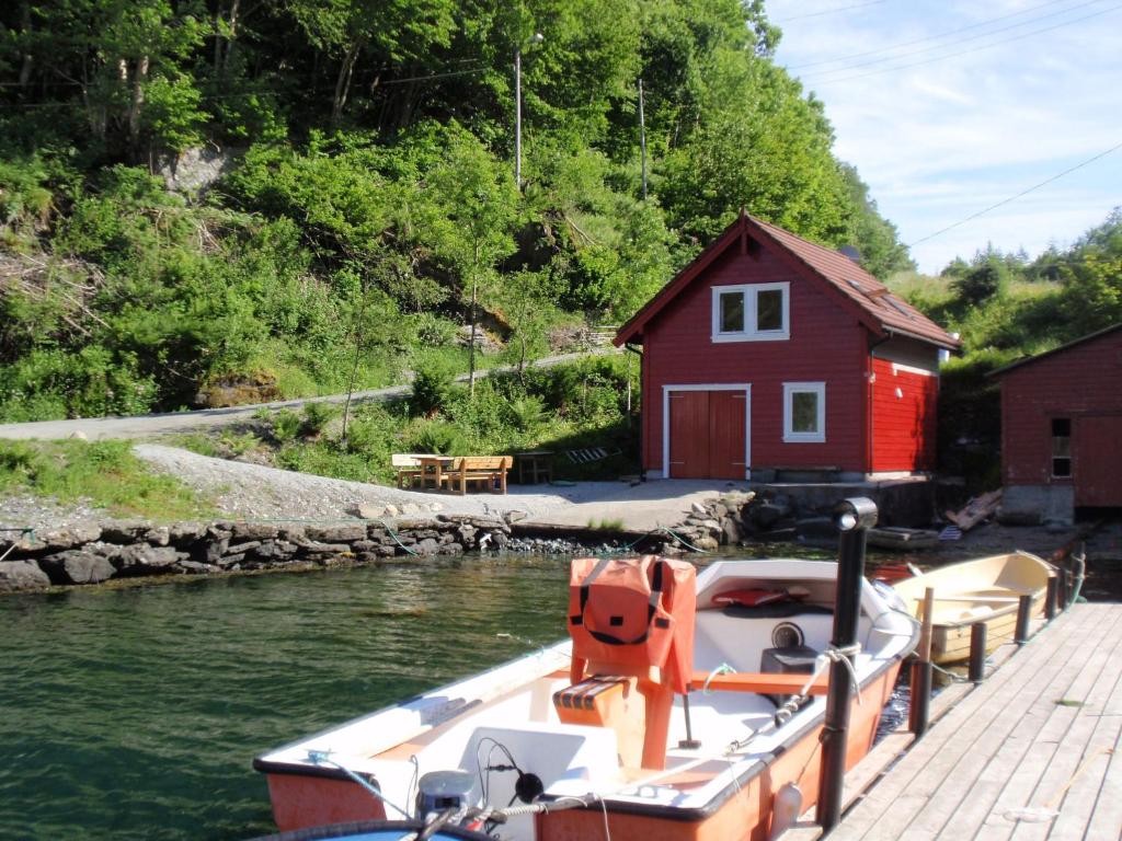Ein Boot liegt neben einem roten Haus vor Anker. in der Unterkunft Holiday Home Tufto by Interhome in Lunde