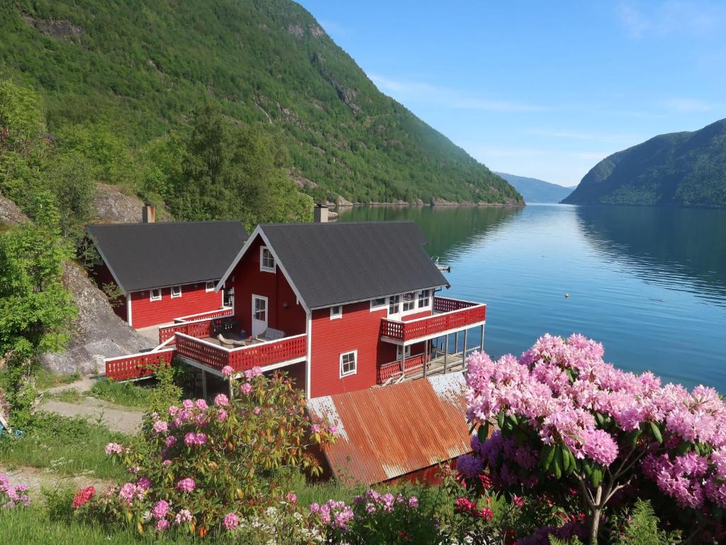 ein rotes Haus am Ufer eines Sees in der Unterkunft Holiday Home Heimdall - FJS604 by Interhome in Arnefjord