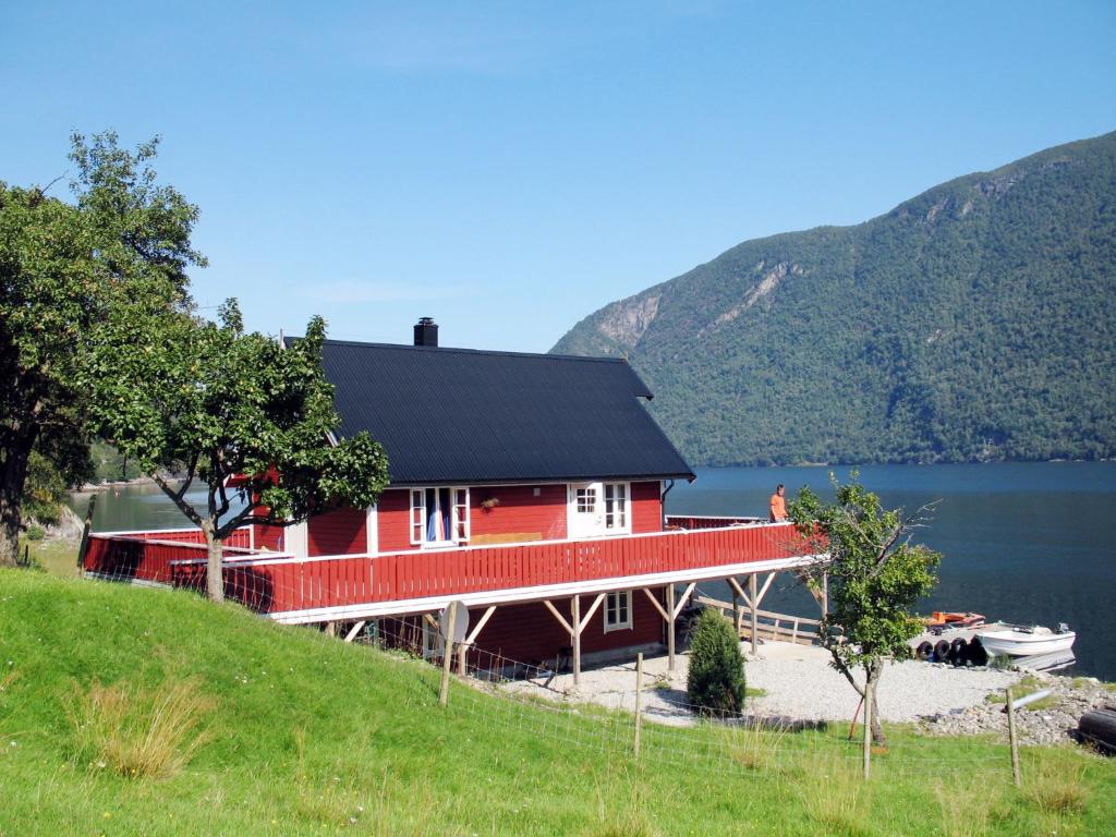 une maison rouge sur la rive d'un lac dans l'établissement Holiday Home Tor - FJS607 by Interhome, à Arnefjord