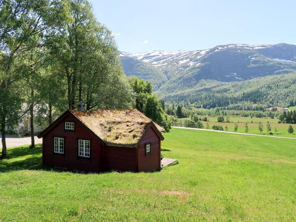 a small house in a field with mountains in the background at Chalet Haukedalspanorama - FJS257 by Interhome in Holsen