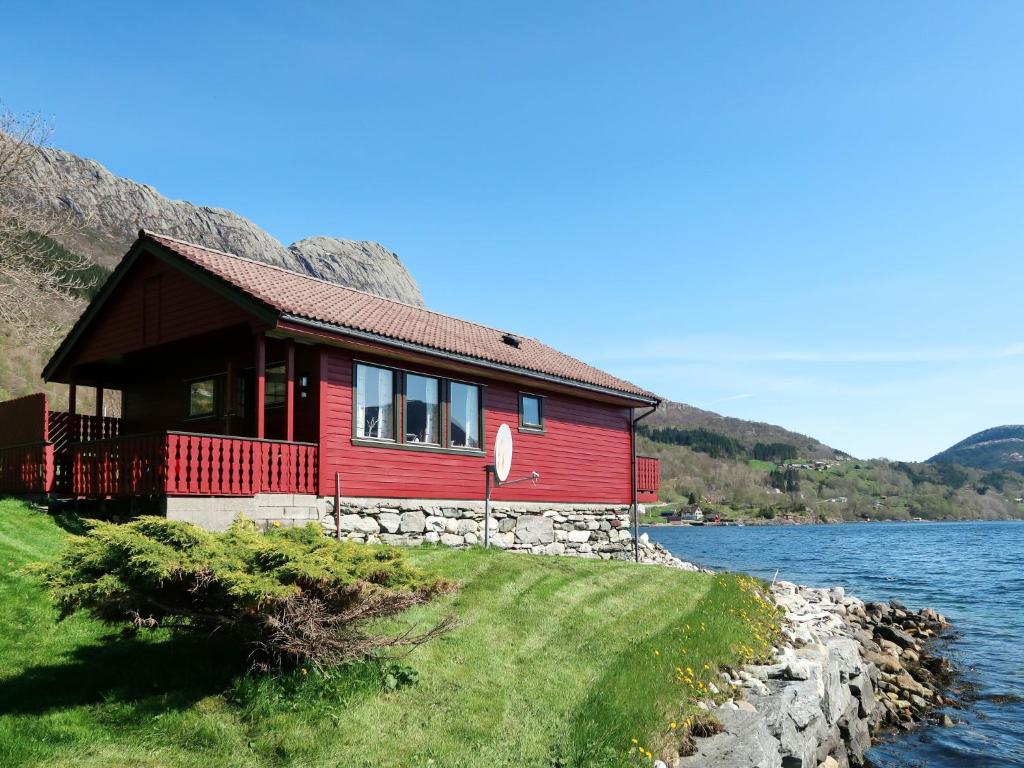 uma casa vermelha na margem de um lago em Holiday Home Nanna - FJS130 by Interhome em Hyllestad