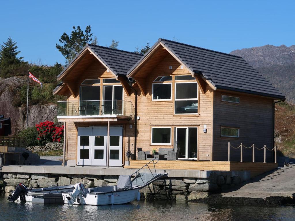 a house on a dock with a boat in the water at Apartment Huglavika - FJH666 by Interhome in Nordhuglo