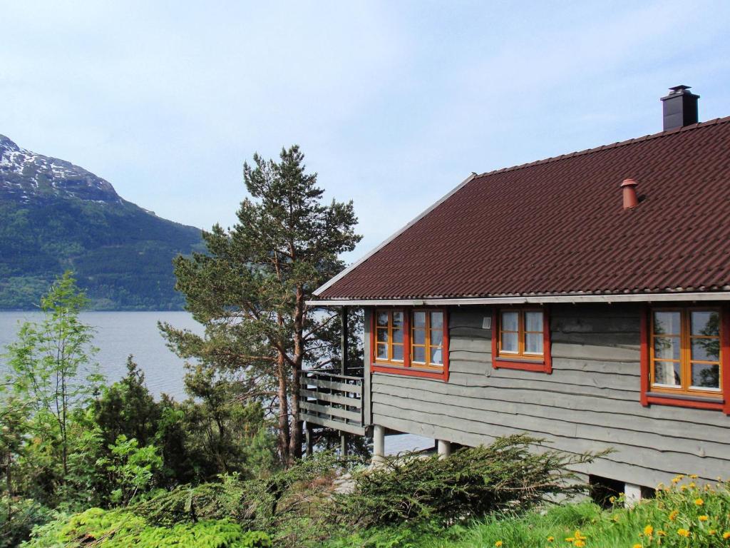 a house with orange windows and a lake at Chalet Eiknes - FJH412 by Interhome in Tjoflot
