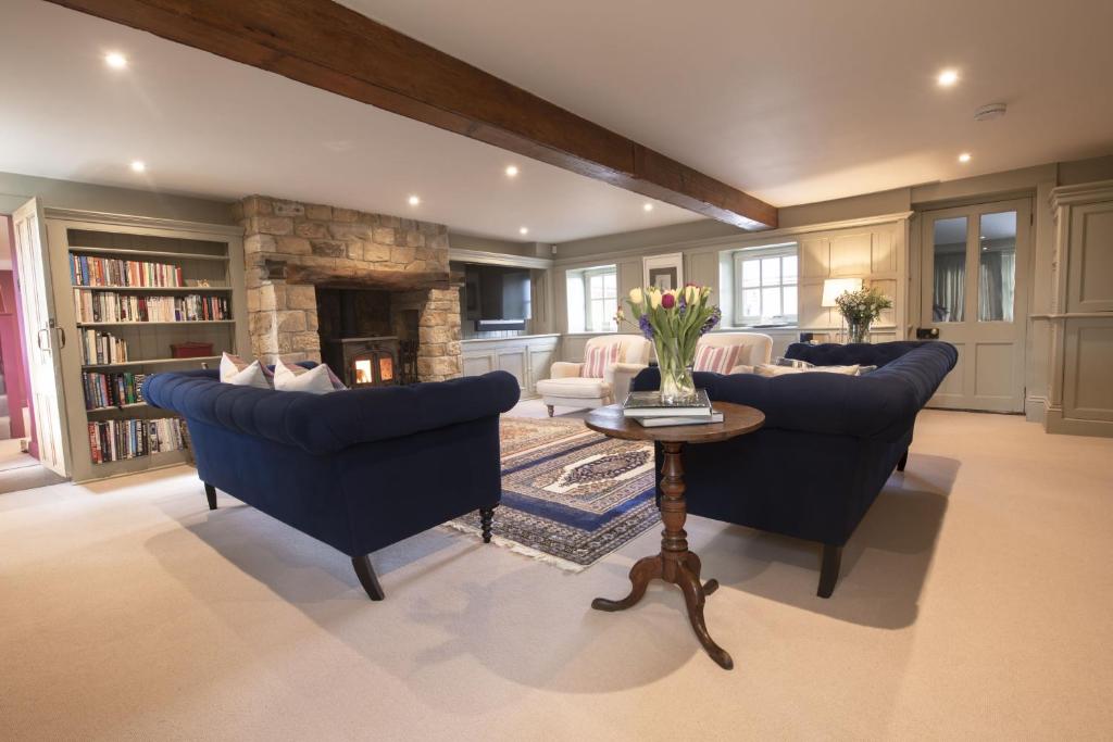 a living room with blue chairs and a stone fireplace at Lanesfoot Farm in Harrogate