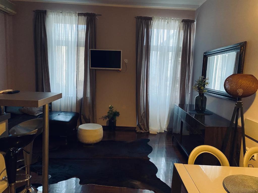 a living room with a television and a table and a room with curtains at Apartment Abbazia in Opatija