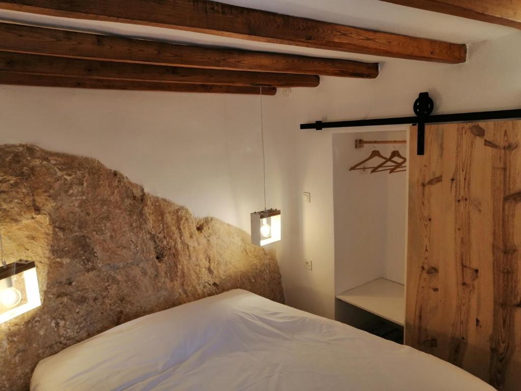 - une chambre avec un lit et un mur en pierre dans l'établissement Blue Vorna, à Áno Sýros