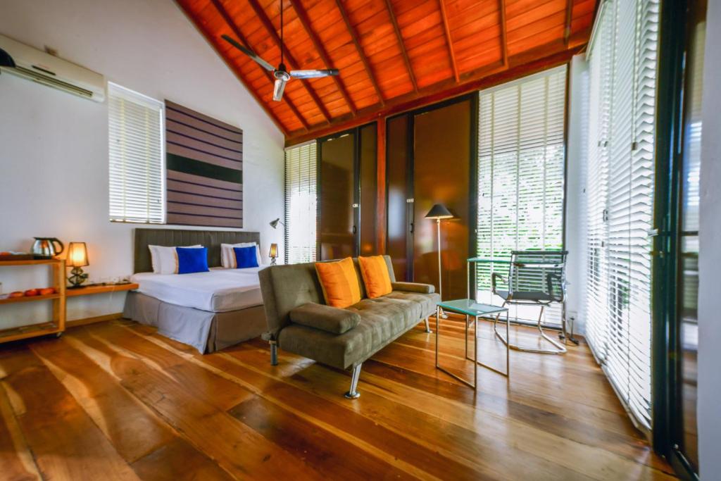 a bedroom with a bed and a couch and a chair at Palm Paradise Cabanas & Villas Beach Resort in Tangalle