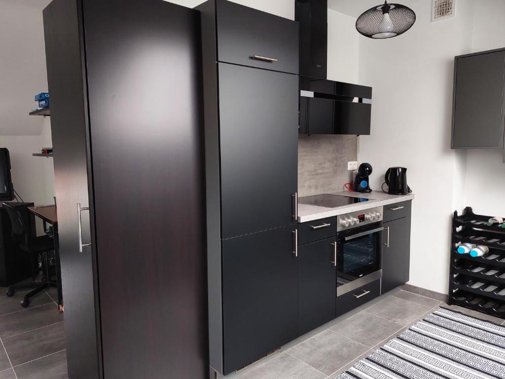 a kitchen with black cabinets and an oven at Appartement meublé Tilff in Esneux