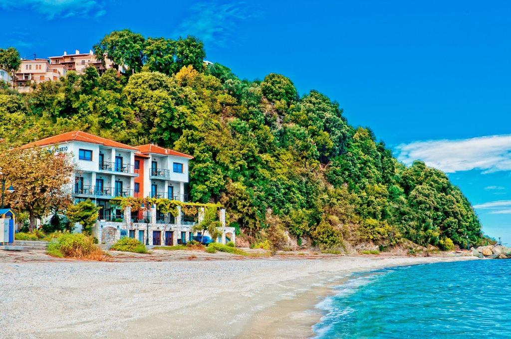 een huis op een heuvel naast het strand bij Hotel Manthos Blue in Agios Ioannis Pelio