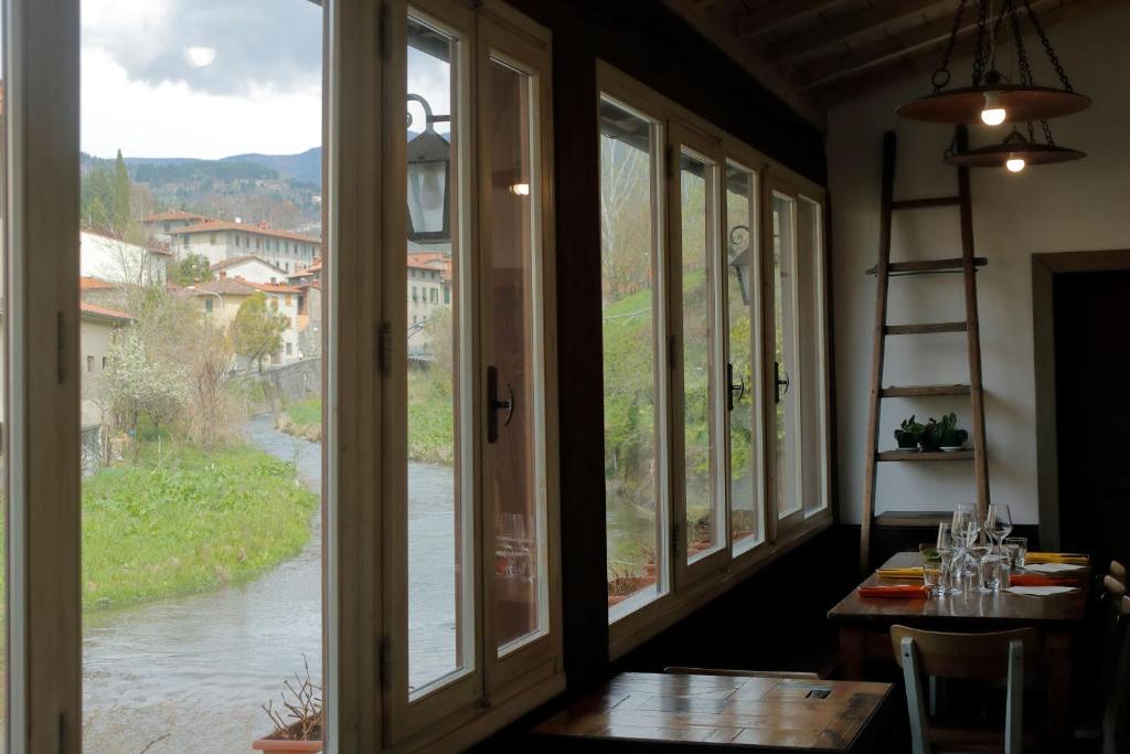 een kamer met ramen en een tafel met uitzicht op een rivier bij L'Ospitale dei Brilli in Stia