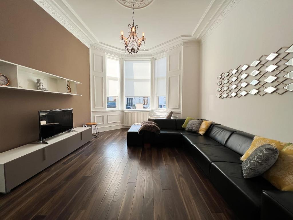 a living room with a black couch and a television at Barfillan House in Glasgow in Glasgow