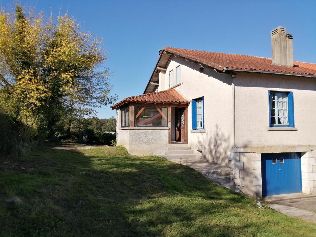a white house with a blue door in a yard at Villa Lélou in Les Mignots