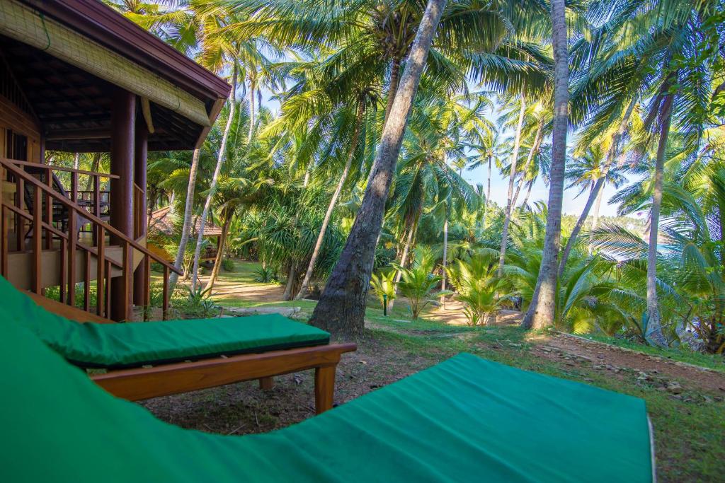 a porch of a house with palm trees at Palm Paradise Cabanas & Villas Beach Resort in Tangalle
