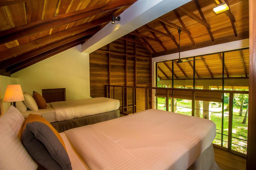 a bedroom with two beds and a large window at Palm Paradise Cabanas & Villas Beach Resort in Tangalle