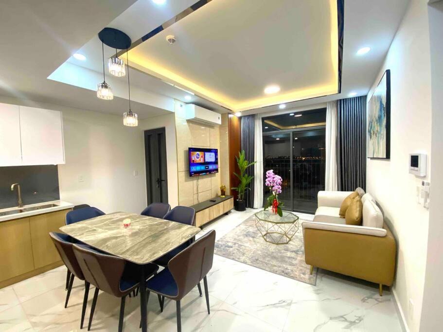 a kitchen and a living room with a table and chairs at Luxury Apartment Asiana Capella Trung tâm Chợ lớn in Ho Chi Minh City
