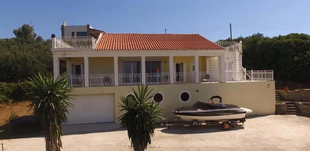 dom z łodzią zaparkowaną przed nim w obiekcie Rose Villa w mieście Agios Stefanos