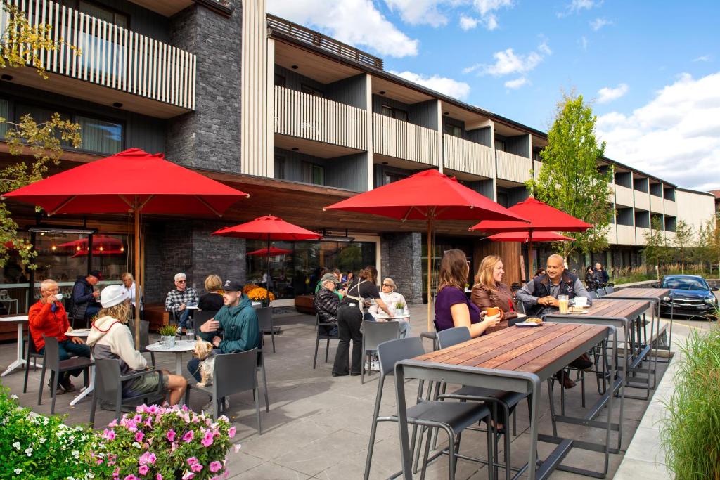 um grupo de pessoas sentadas em mesas com guarda-chuvas vermelhos em Banff Aspen Lodge em Banff