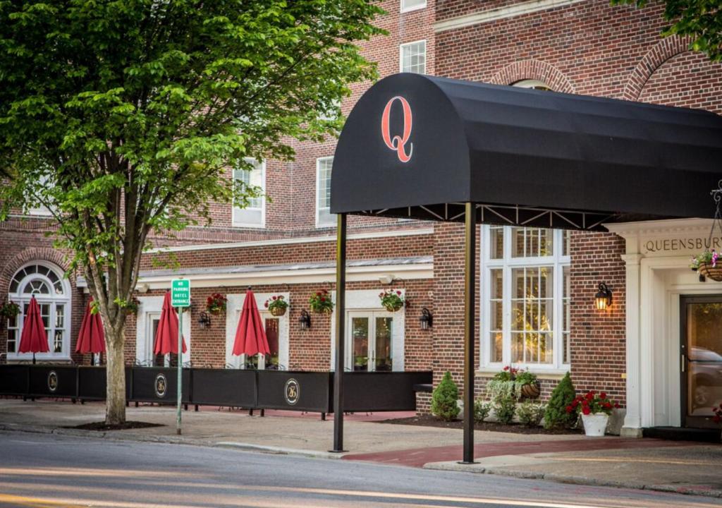 a restaurant with a black awning in front of a building at The Queensbury Hotel in Glens Falls